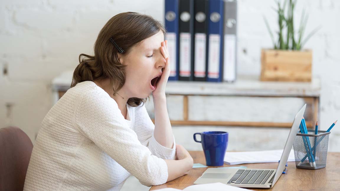 Woman at her kitchen table yawning.