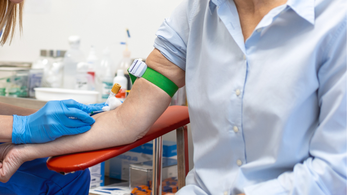 Preparation for blood test with senior woman by female doctor medical uniform on the table in white bright room. Nurse pierces the patient's arm vein with needle blank tube.