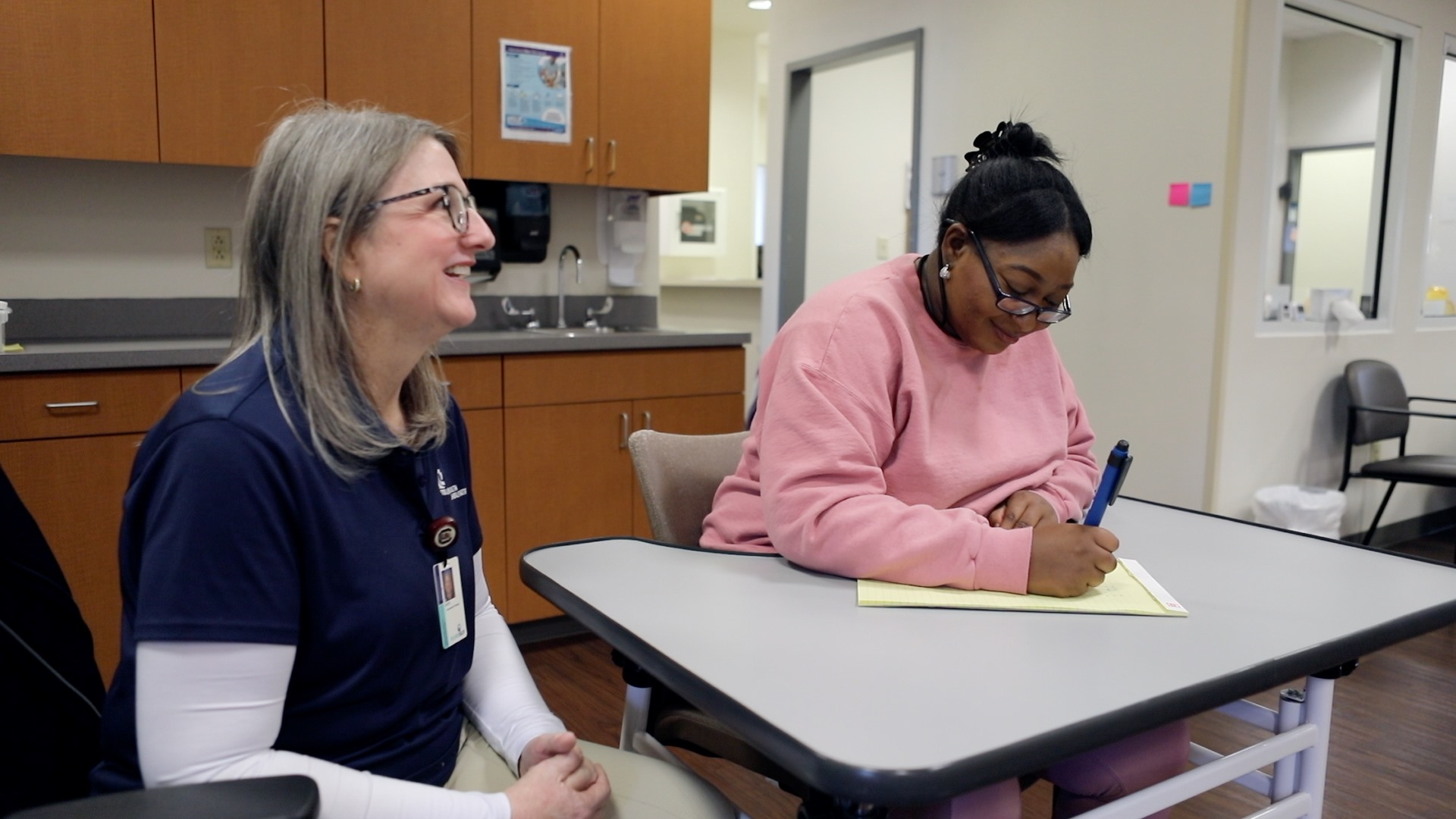 Alexis Prue writes while a Tidelands Health therapist oversees.