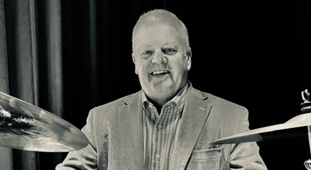 A man playing drums. The photo is black and white.