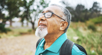 Senior man enjoying the outdoors by breathing deeply on hiking trail.