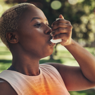 Woman using inhaler outside in a park
