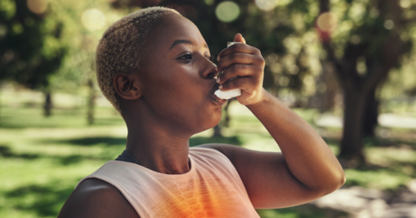 Woman using inhaler outside in a park
