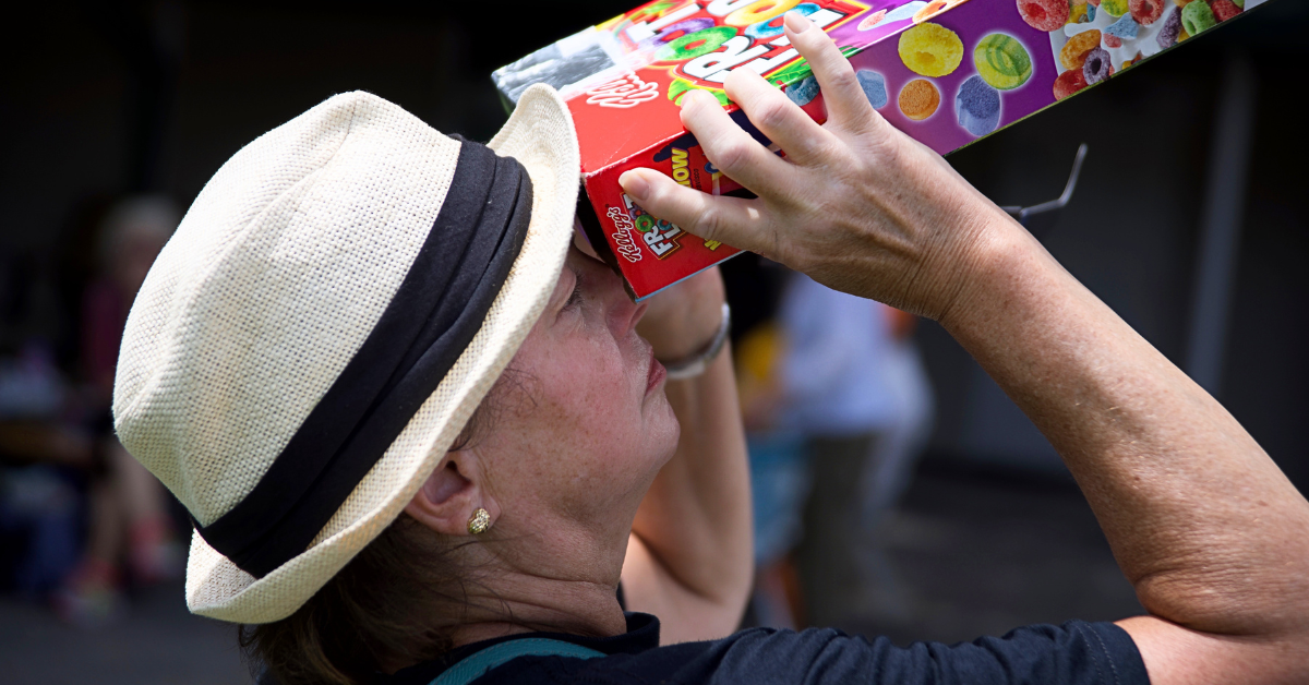 A person looking at the eclipse using a cereal box