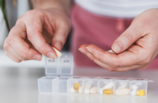 Closeup of medical pill box with doses of tablets for daily take a medicine with different white, yellow drugs and capsules