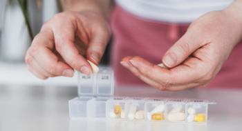 Closeup of medical pill box with doses of tablets for daily take a medicine with different white, yellow drugs and capsules