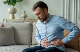 A man suffers from abdominal pain while sitting at home on the couch.