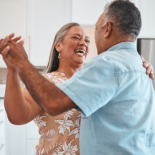 Happy senior couple, dance and laughing in kitchen at home.
