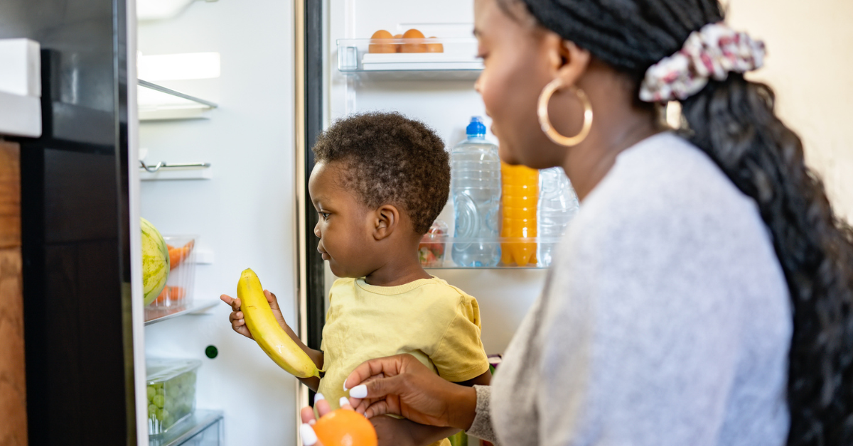 Cheerful African-American mother and son in the kitchen. Son helps a mother to bring in groceries after a grocery-shopping
