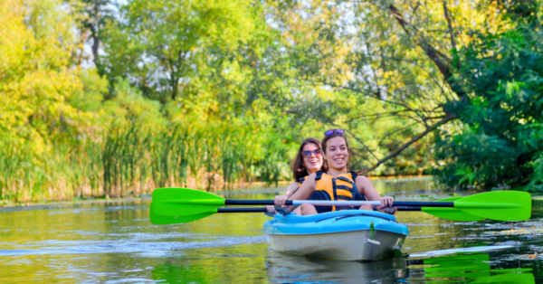 mother and child paddling in kayak on river canoe tour