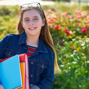 Blond kid student girl with notebook and backpack in the park back to school