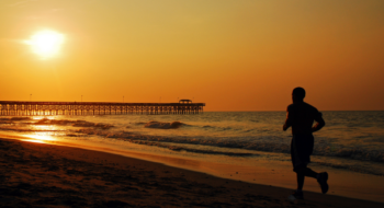 A Jogger runs towards the sun during a morning jog