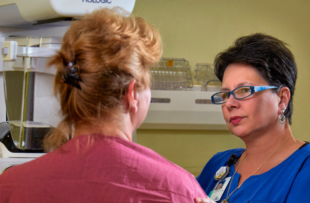 A mammography technician comforts a patient during her mammogram.