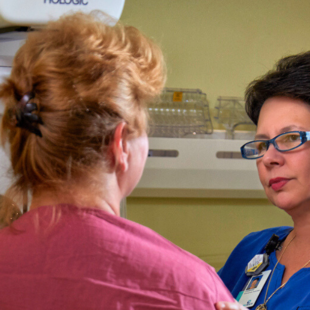 A mammography technician comforts a patient during her mammogram.