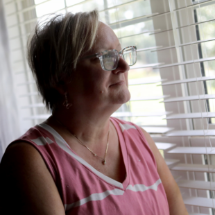 Tara Cook stares out of a window, smiling.