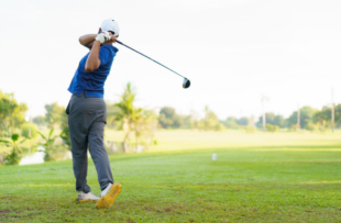 male amateur golfer is enjoy playing golf at golf course in morning, he is showing his beautiful swing during tee off. Man playing golf.