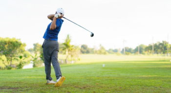 male amateur golfer is enjoy playing golf at golf course in morning, he is showing his beautiful swing during tee off. Man playing golf.