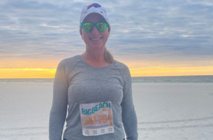 Lisa Hadwin stands on a beach after completing a half marathon.