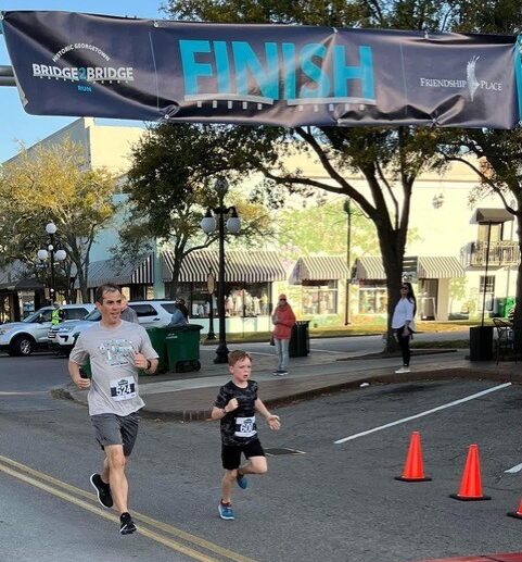 Dr. Alex Duvall and his youngest son cross the finish line at the 2024 Bridge2Bridge Run.