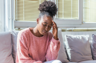 Portrait of a young girl sitting on the couch at home with a headache