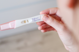 Close up top view of a woman holding a negative pregnancy test, blurred background