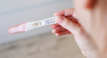 Close up top view of a woman holding a negative pregnancy test, blurred background