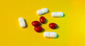 White and red pills on a yellow background. Top view.