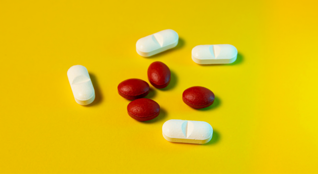 White and red pills on a yellow background. Top view.