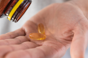 Man pouring fish oil capsules with omega 3, vitamin D in hand from medicine bottle. Nutritional supplement. Health support and treatment concept. Close up