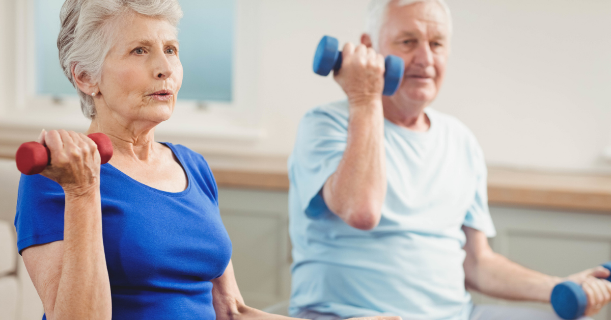An older man and woman lifting weights while sitting down.