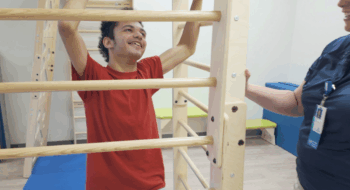 16-year-old boy learns and plays on new equipment that resembles monkey bars.