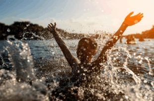 child swim in lake or river and have fun with drops;