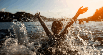 child swim in lake or river and have fun with drops;