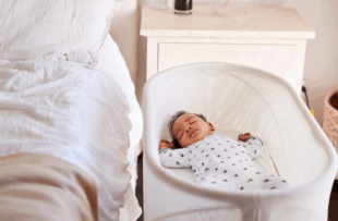 hree month old baby asleep in his cot beside the bed in his mother's bedroom