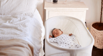 hree month old baby asleep in his cot beside the bed in his mother's bedroom