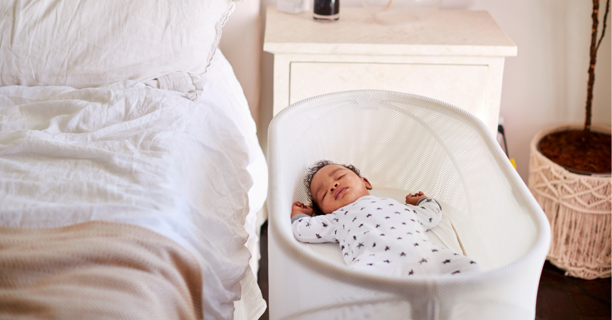 hree month old baby asleep in his cot beside the bed in his mother's bedroom