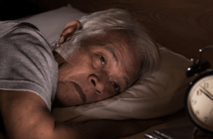 A depressed senior man lying in bed cannot sleep from insomnia