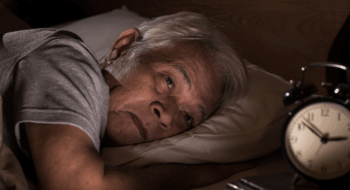 A depressed senior man lying in bed cannot sleep from insomnia