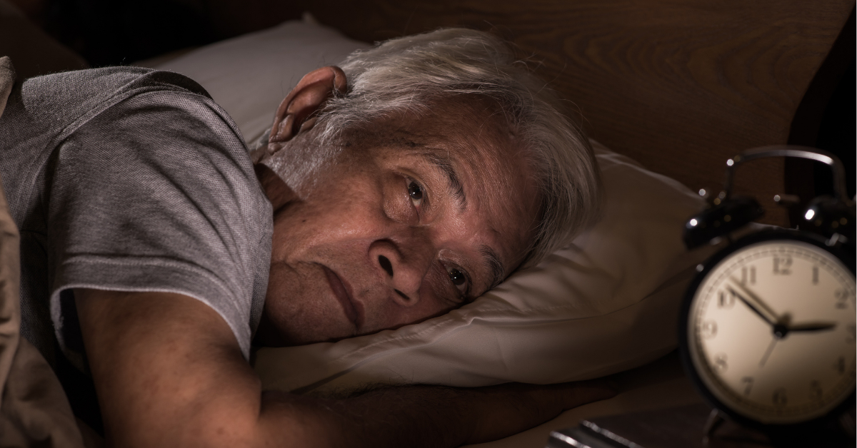 A depressed senior man lying in bed cannot sleep from insomnia