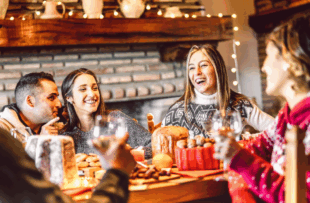 Millenial people tasting Christmas sweets at home supper party - New year's eve and winter holiday concept with young friends having fun eating together at evening