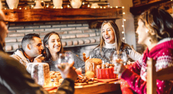 Millenial people tasting Christmas sweets at home supper party - New year's eve and winter holiday concept with young friends having fun eating together at evening