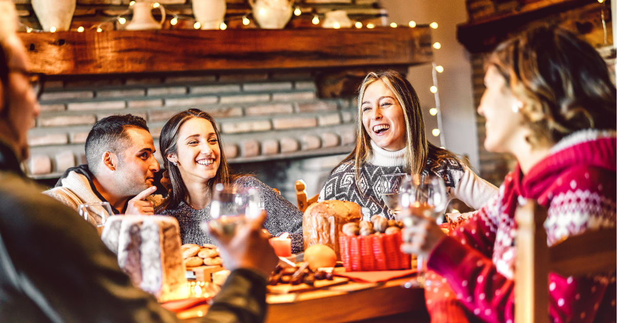 Millenial people tasting Christmas sweets at home supper party - New year's eve and winter holiday concept with young friends having fun eating together at evening