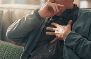 Home, hands and old man with chest pain, cough and cardiac symptoms in lounge. Closeup, hypertension or elderly person with heart attack signs, retirement and viral infection with illness or asthma