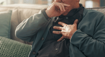 Home, hands and old man with chest pain, cough and cardiac symptoms in lounge. Closeup, hypertension or elderly person with heart attack signs, retirement and viral infection with illness or asthma