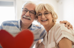 Smiling senior couple holding up a heart