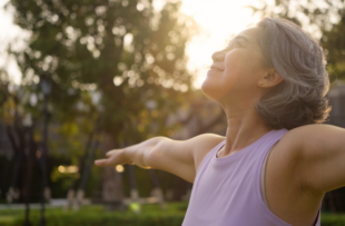 middle age mindful happy old woman open arm yoga deep calm stress relief outdoor nature public park sun light